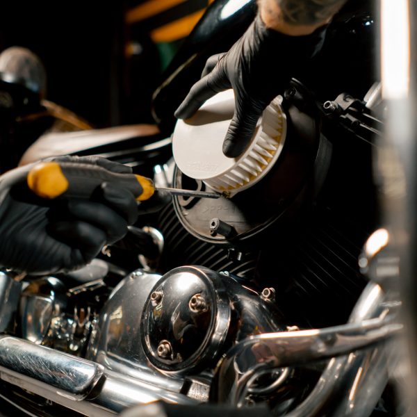 close up In a motorcycle repair shop a mechanic takes out a filter to replace it with a new one