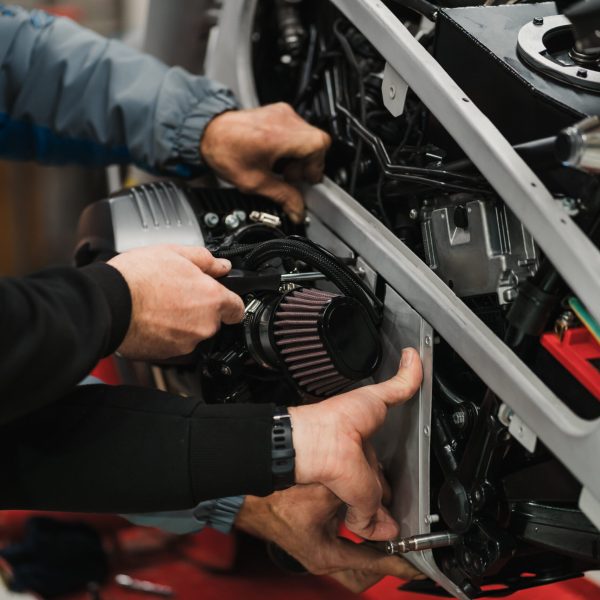 Repairman repair motorcycle, maintenance in garage. Mechanic fixing bike in a modern shop